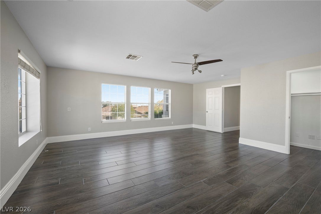 Generous windows illuminate the dark wood-look plank tile floors and clean white trim work.