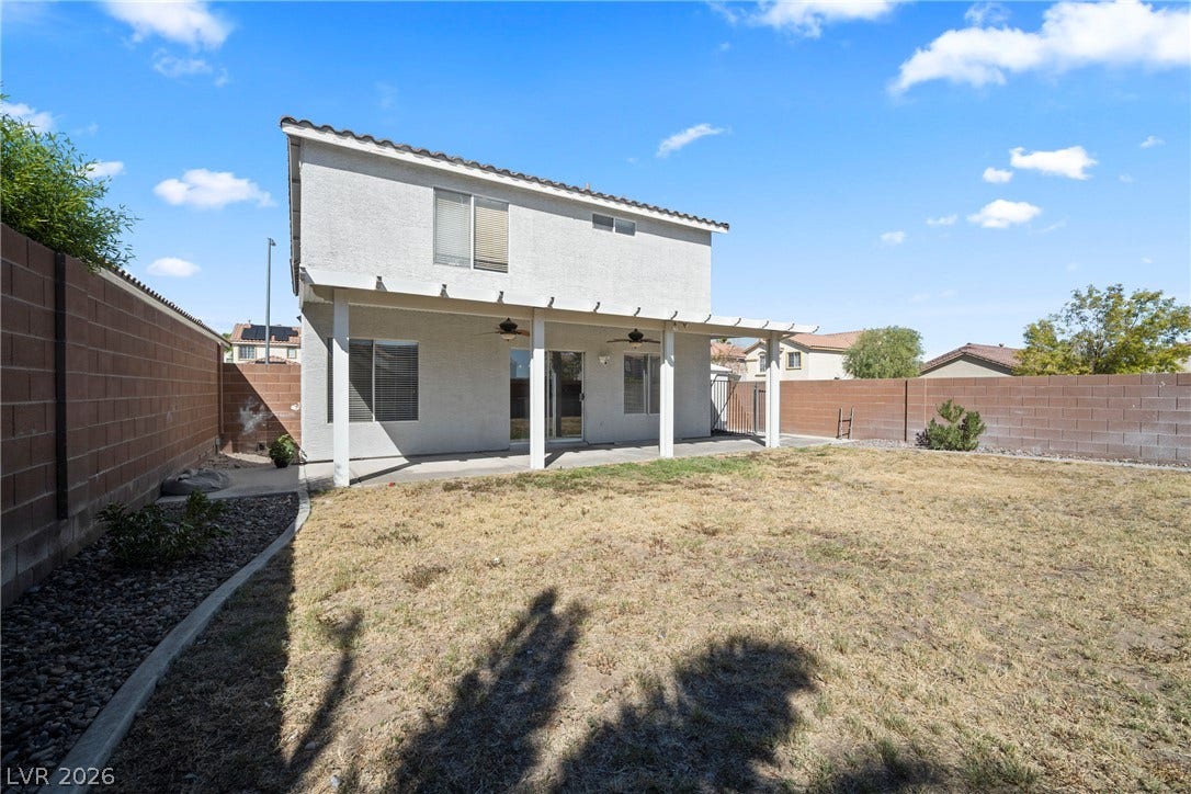 A spacious backyard features a covered patio and a secure block wall perimeter.