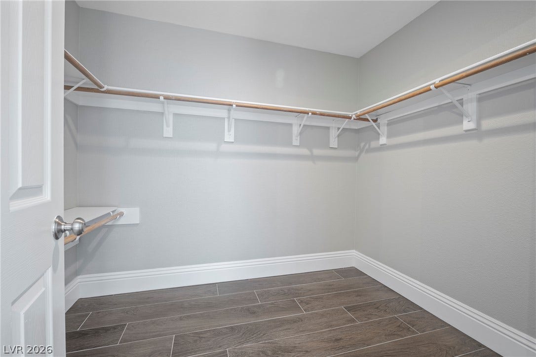 A spacious walk-in closet includes ample shelving and wood-look flooring.