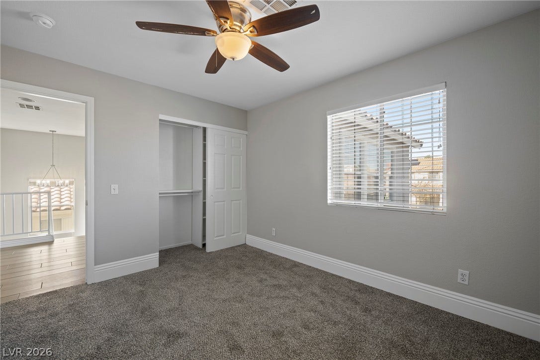 Plush carpeting and a large window define this comfortable, light-filled bedroom space.