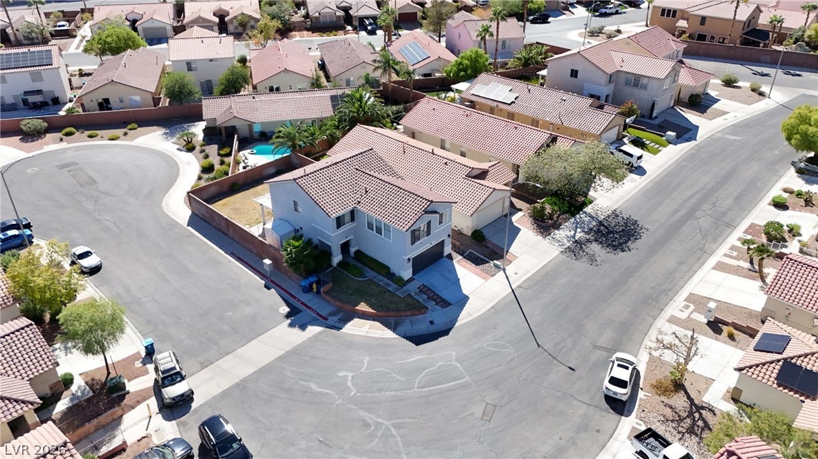 An aerial perspective showcases a tile-roofed home nestled on a spacious corner lot.
