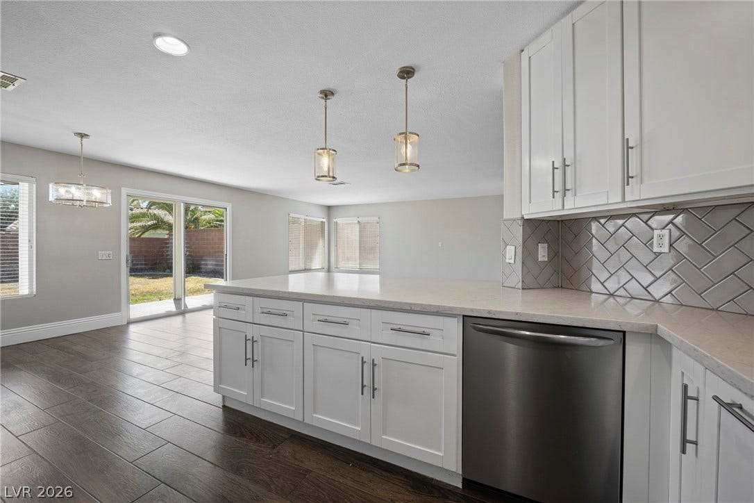 An open kitchen layout transitions smoothly into the dining space over rich plank flooring.