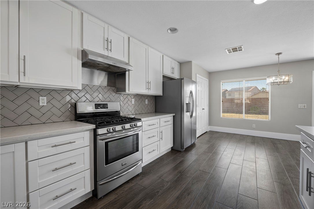 Sleek modern cabinetry and tiled backsplash frame this culinary space adjoining a bright dining area.
