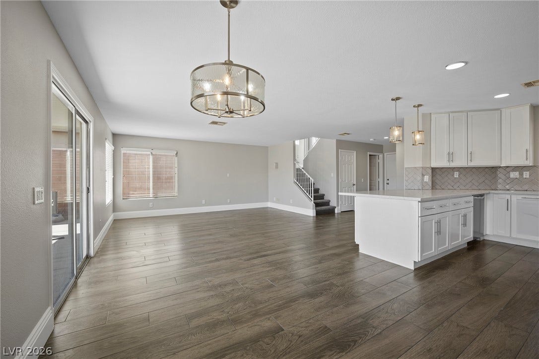 Polished hard surface flooring flows through a bright, open space adjacent to the kitchen.