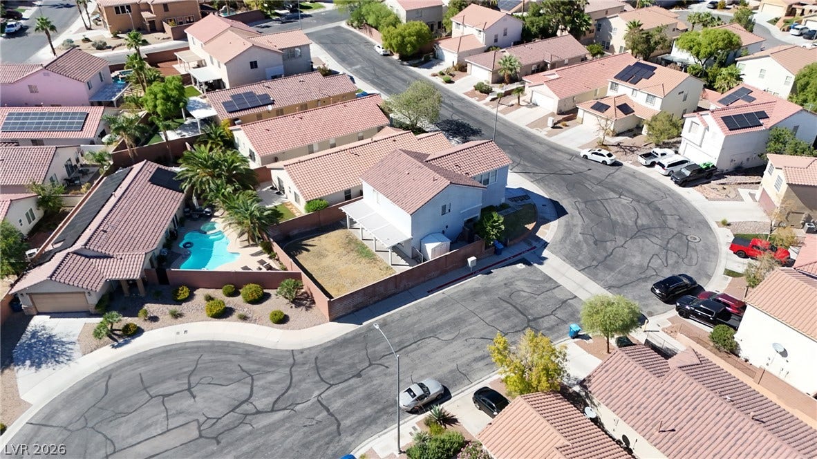An aerial perspective showcases a quiet residential cul-de-sac surrounded by tile-roofed homes.