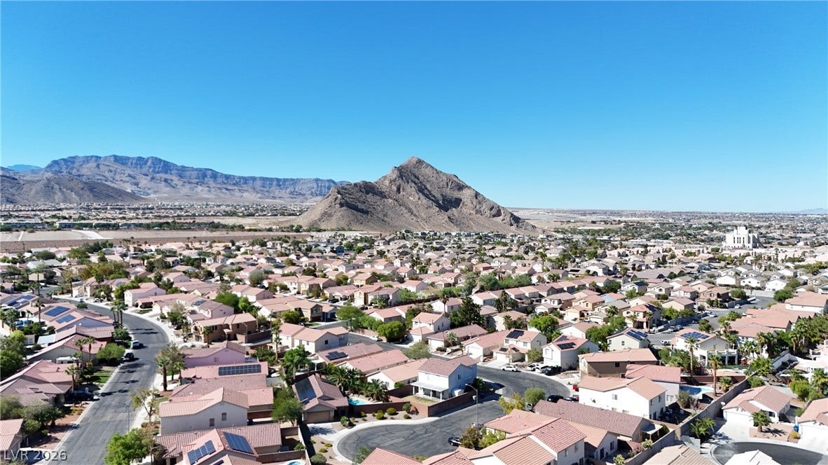 Dramatic mountain vistas rise above a sprawling neighborhood under clear blue skies.