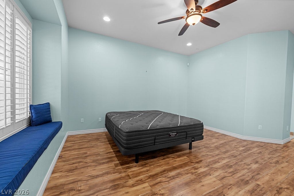 This spacious bedroom features wood flooring, recessed lighting, and a built-in window seat for added comfort.