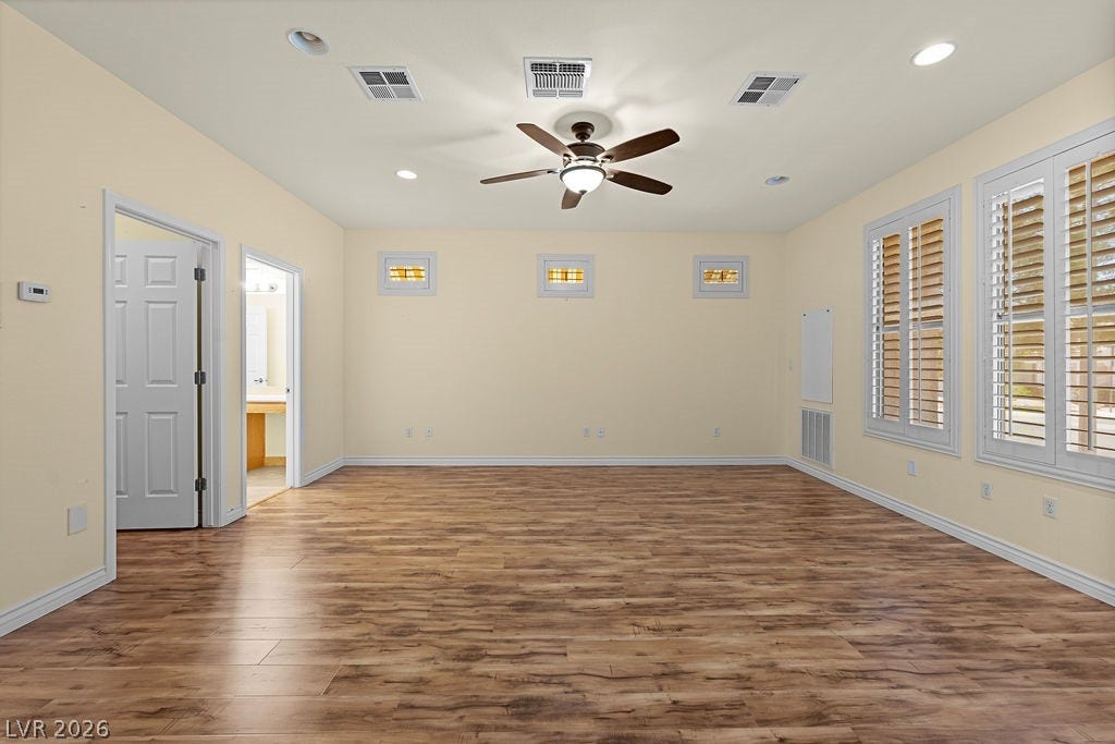 This spacious area features warm flooring, recessed lighting, and ample natural light through window shutters.