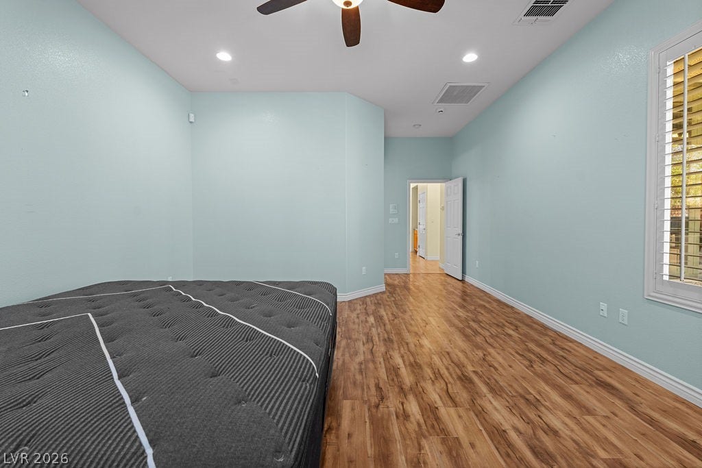 This spacious bedroom features ample natural light and durable wood flooring.