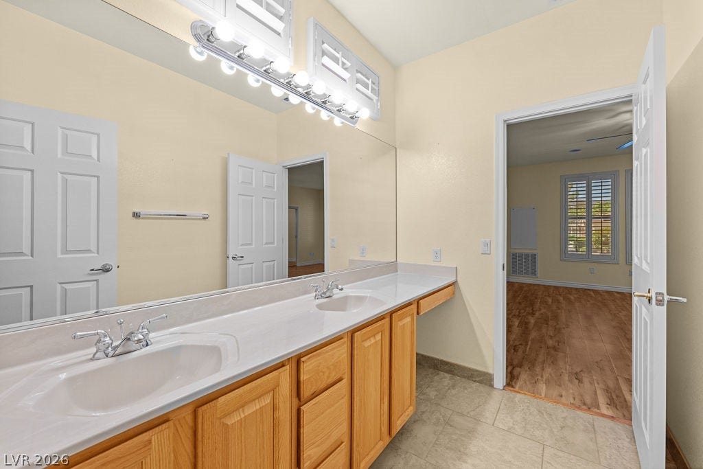 This bathroom features a double vanity and sleek countertops, offering practicality and ample storage.