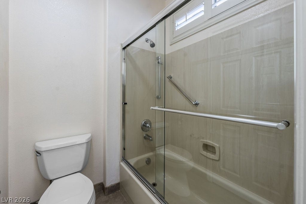 This clean and bright bathroom features a combined shower and tub, offering practical design.