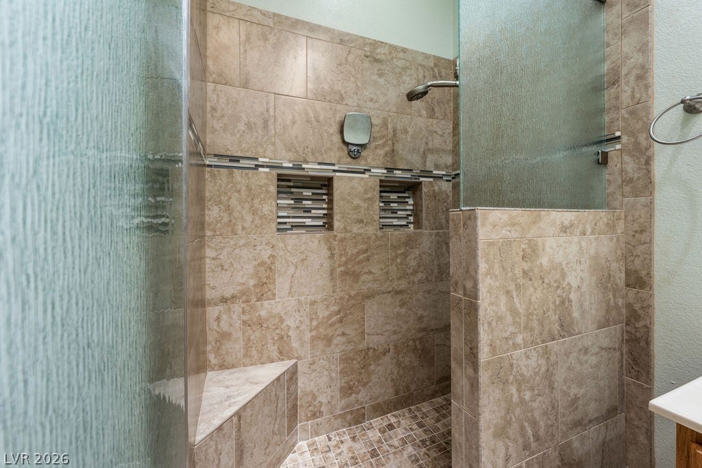 This spacious shower features elegant tile work and integrated niches for a refined bathing experience.