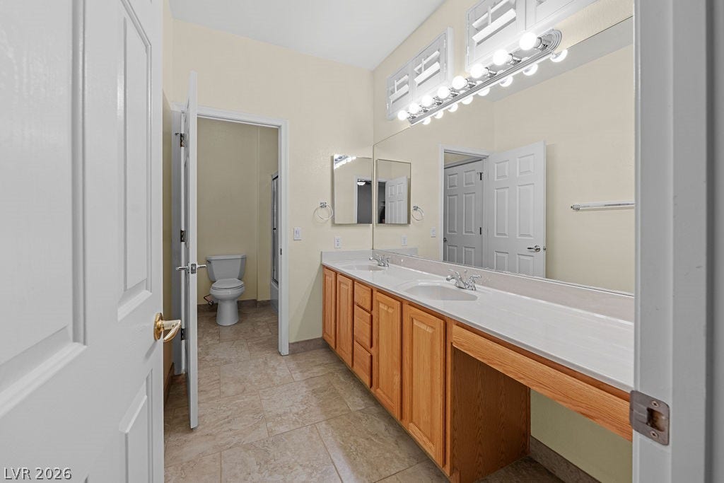 This spacious bathroom offers dual vanities, generous counter space, and a separate water closet.