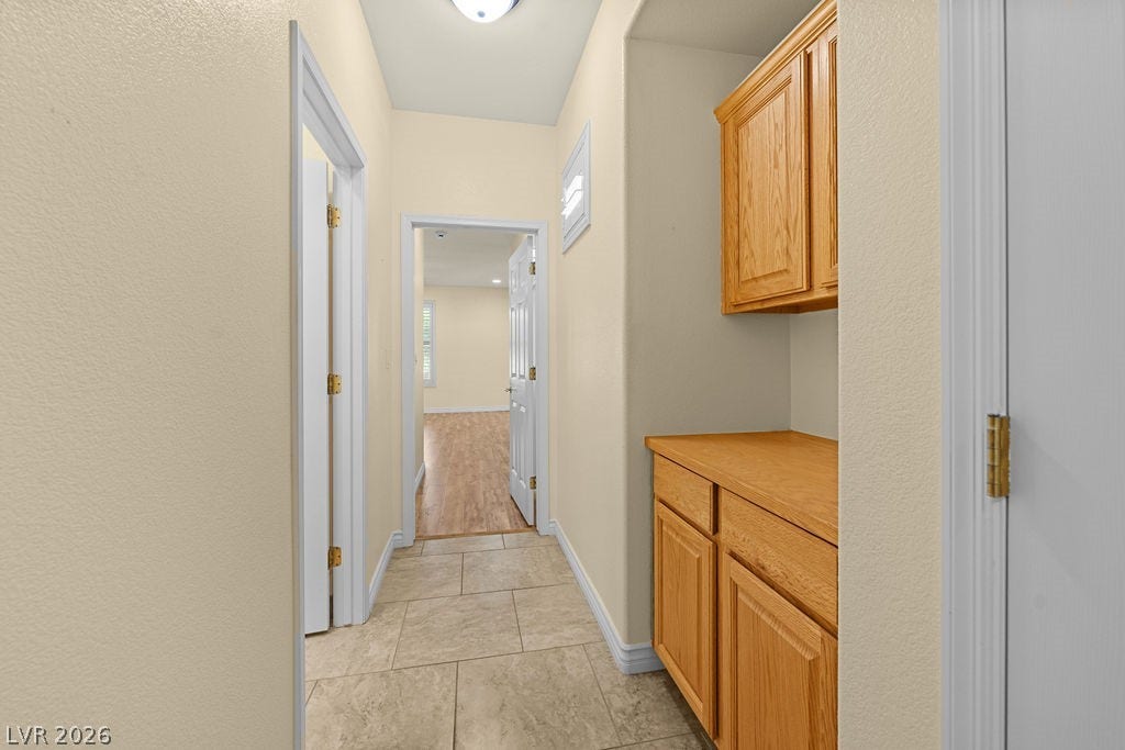 This interior hallway features warm flooring and cabinetry, leading to another spacious room.