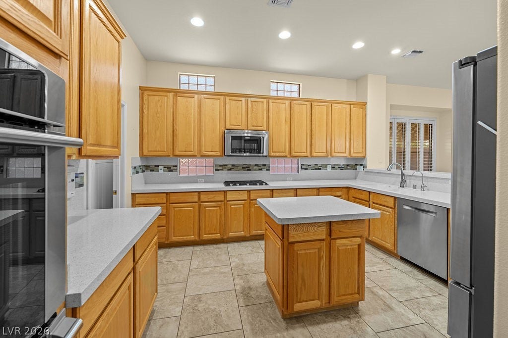 This spacious kitchen features ample cabinetry, an island, and modern stainless steel appliances.