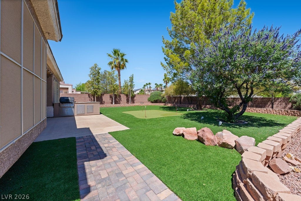 Enjoy outdoor leisure in this private yard featuring a putting green and outdoor kitchen.