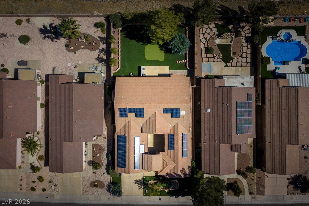 This aerial view showcases a residential property featuring a backyard pool and solar panels.