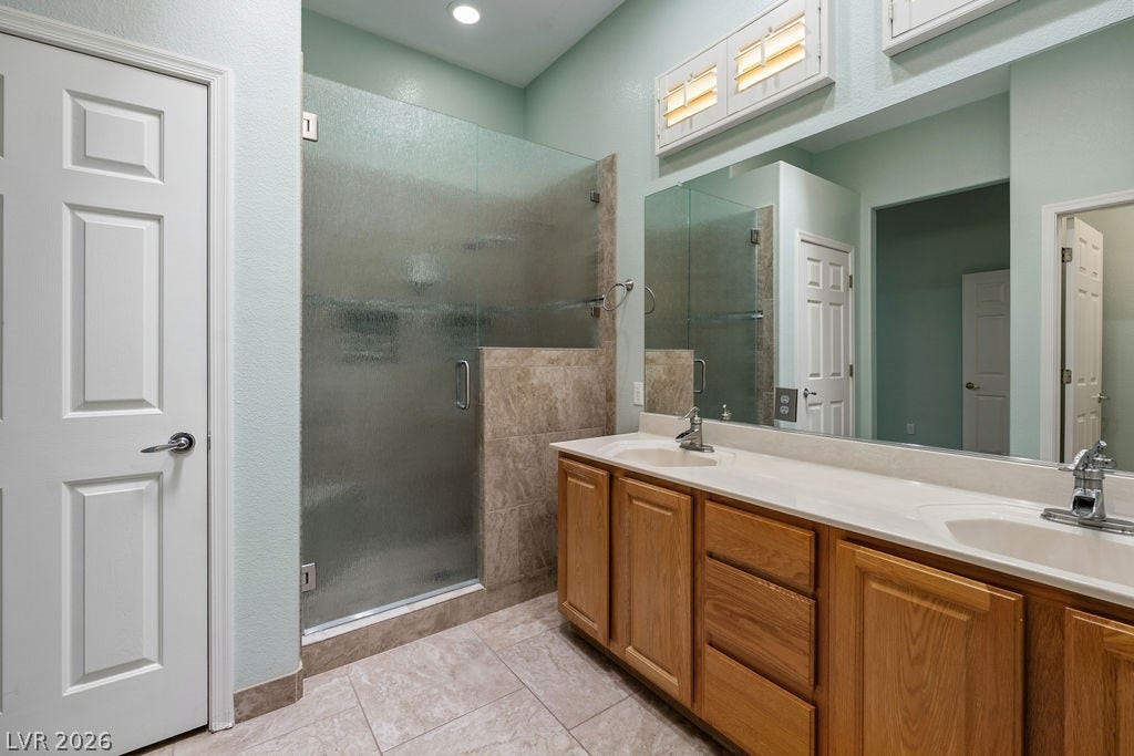 This spacious bathroom offers a double vanity and a glass-enclosed shower, perfect for daily routines.