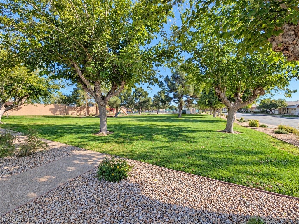 3708 Heritage Avenue, Las Vegas, NV 89121 Mature trees shade a manicured lawn alongside a paved walkway in a peaceful neighborhood park.