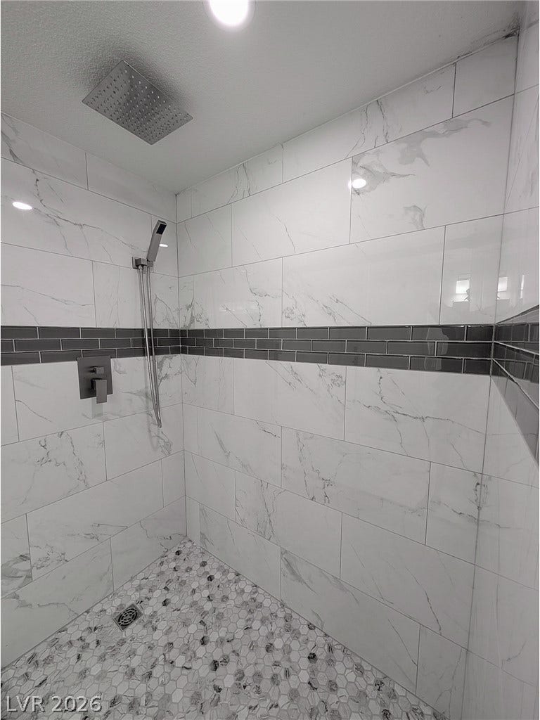 3708 Heritage Avenue, Las Vegas, NV 89121 Elegant tile details and a rainfall showerhead define this modern walk-in shower design.