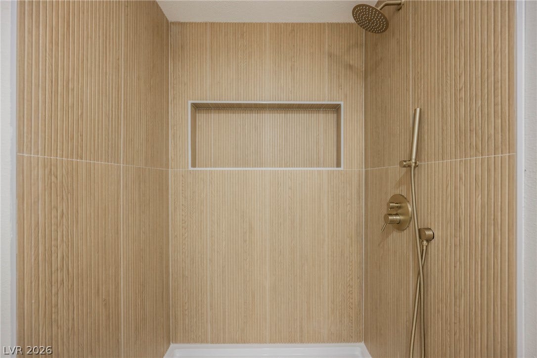 223 W Basic Road, Henderson, NV 89015 Richly textured vertical tiling pairs beautifully with premium gold fixtures in this modern shower.