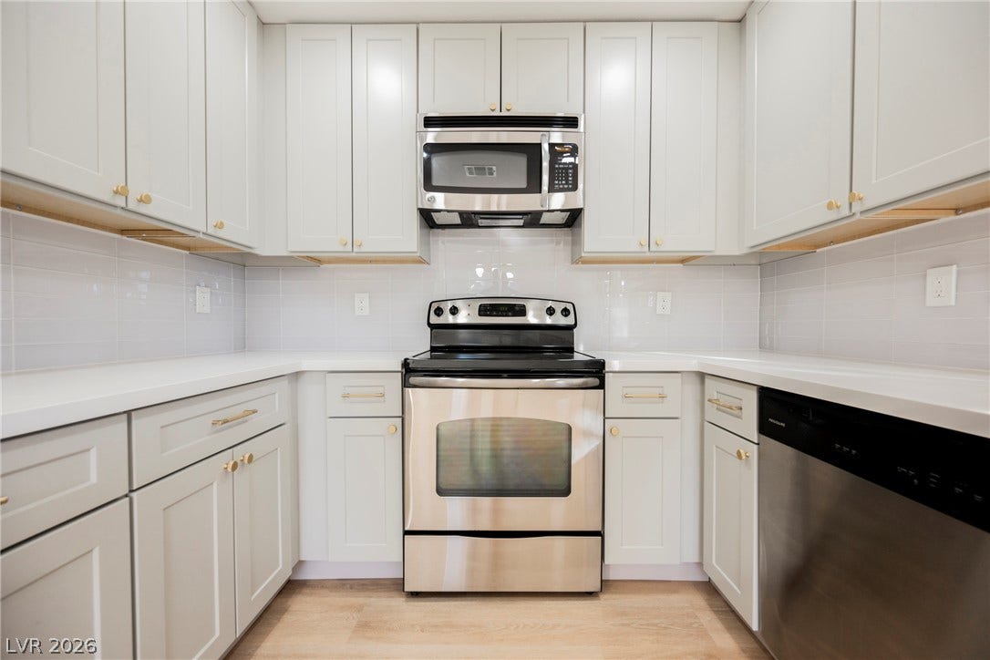 223 W Basic Road, Henderson, NV 89015 Crisp white cabinetry paired with modern appliances highlights this sleek kitchen workspace.