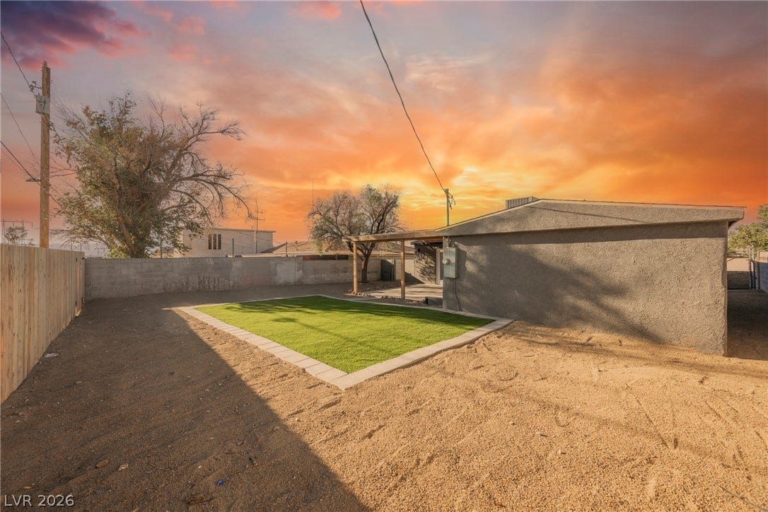 223 W Basic Road, Henderson, NV 89015 A spacious backyard features stucco exteriors and a neat green lawn section under vast skies.
