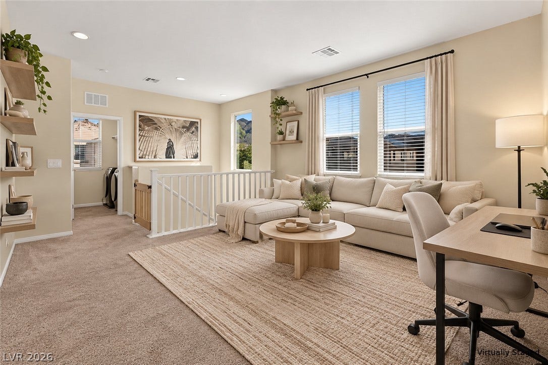 Sunlight streams through large windows into this spacious upper-level living area with recessed lighting.