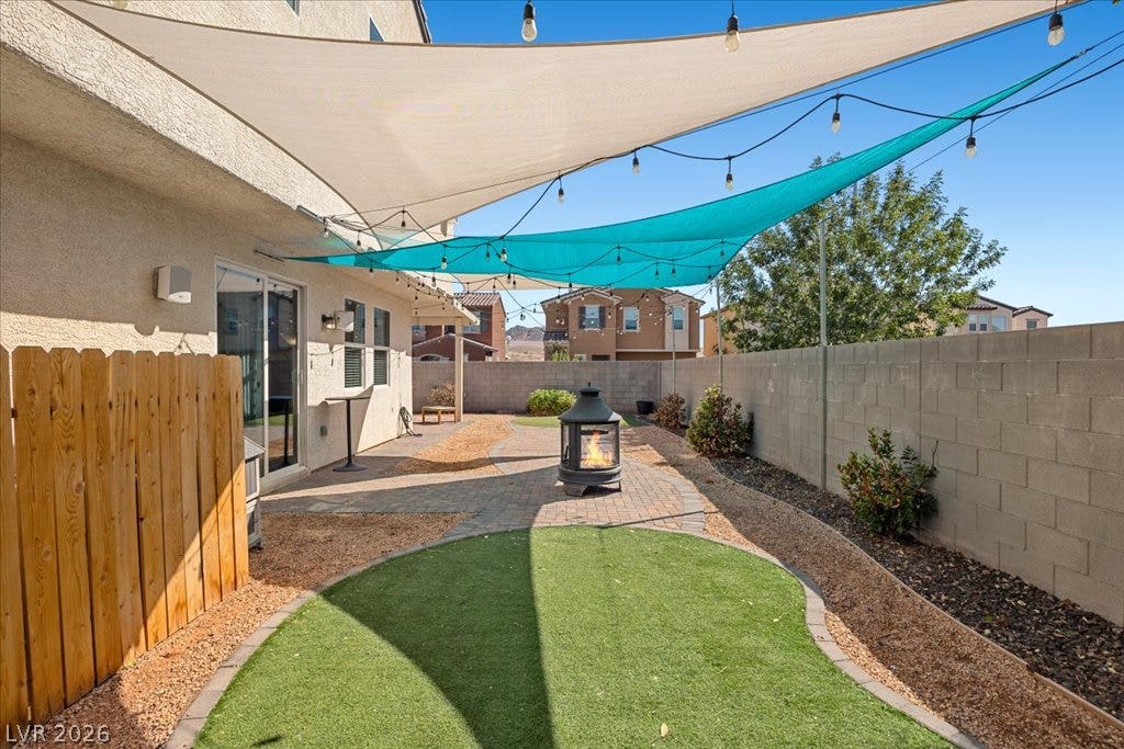 A private backyard patio area is flanked by stone-paved paths and a block wall.