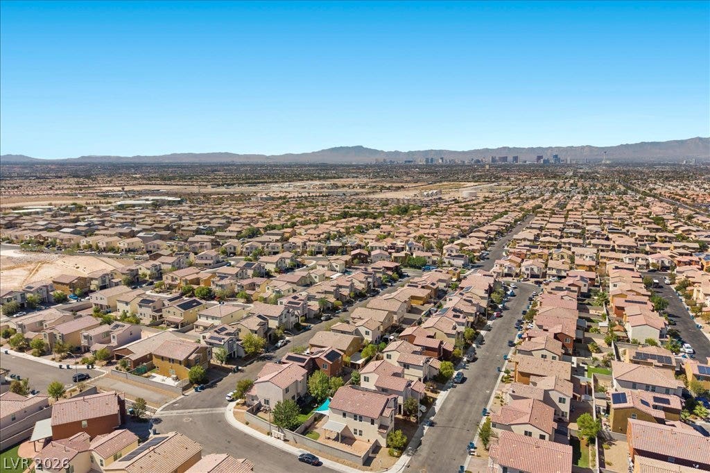 An aerial perspective showcases a residential neighborhood stretching toward distant mountain ranges.