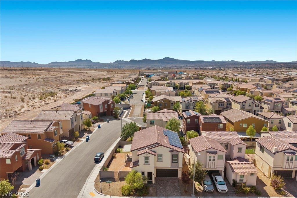 Distant mountain ranges border this suburban residential neighborhood under clear desert skies.