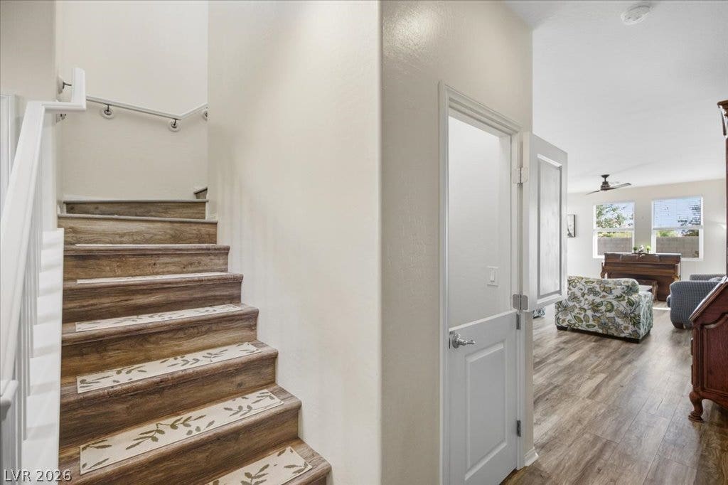 Warm wood-look flooring connects the staircase landing directly to a light-filled living area with new flooring (2026).