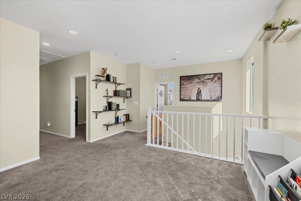 A versatile upper-level loft features wall shelving, recessed lighting, and soft carpeting.