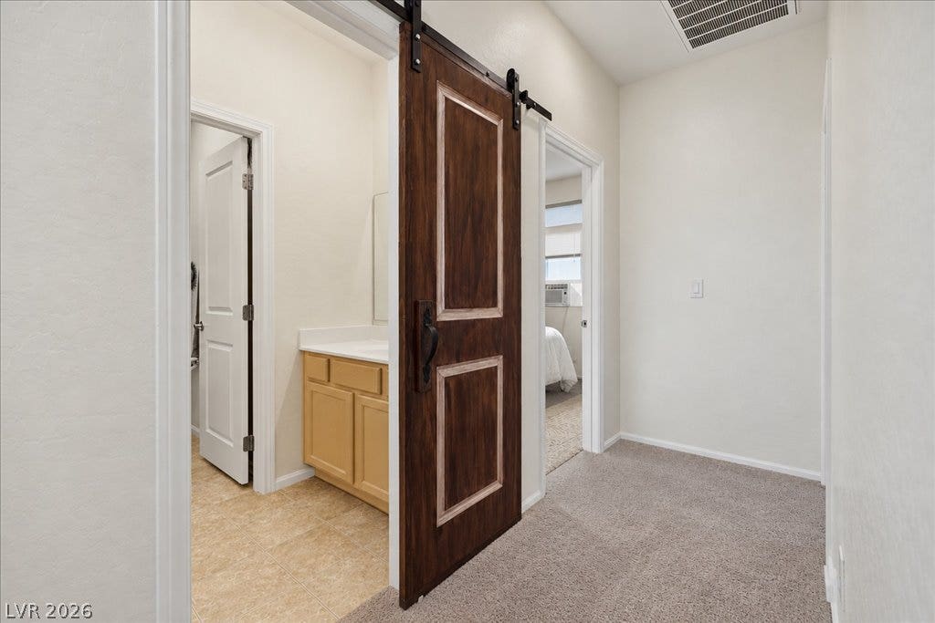 An eye-catching sliding barn door opens to reveal a classic vanity and tile flooring.