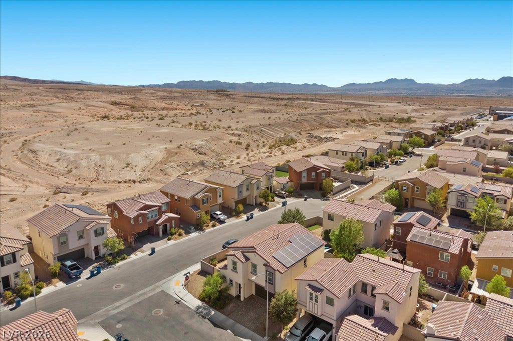 Distant mountain ridges frame this desert neighborhood featuring tile roofs and solar panels.