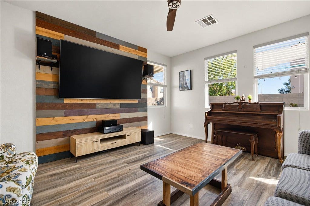 Warm laminate flooring (2026 install) and an accent wall highlight this light-filled family room.