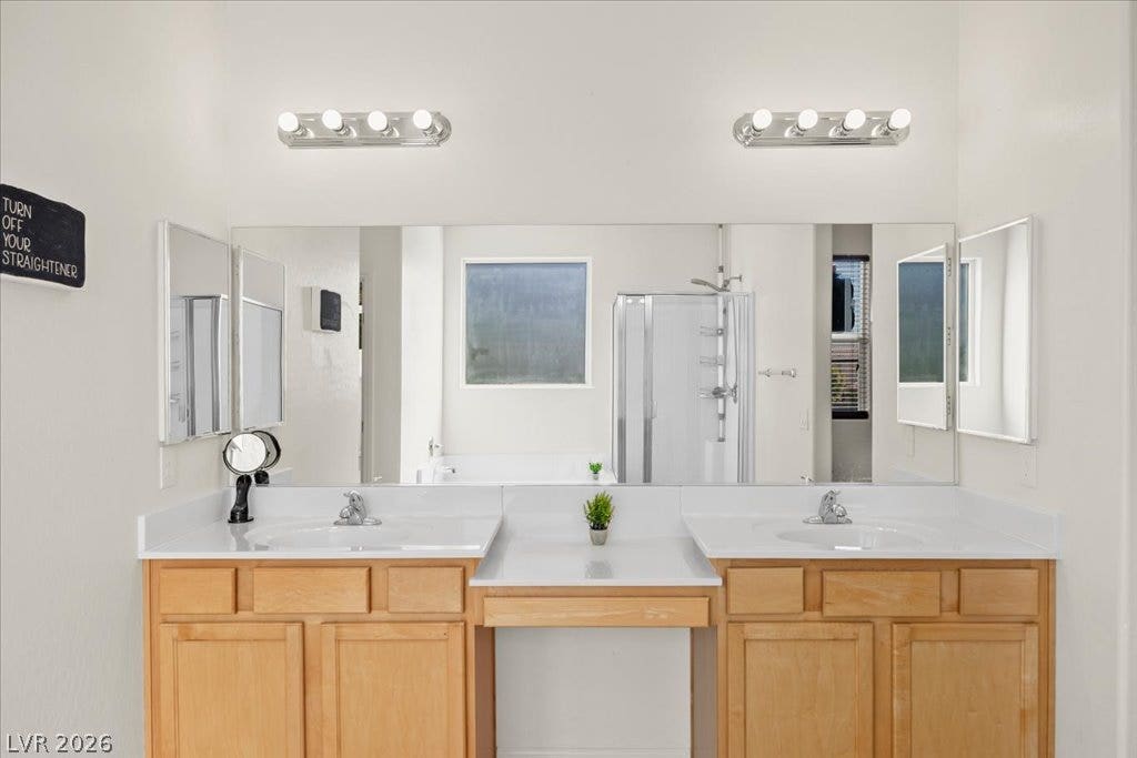 An expansive double vanity with warm wood cabinetry centers this light-filled bathroom design.