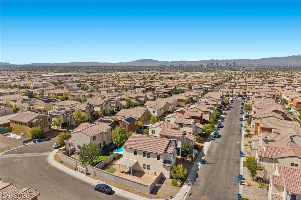 An aerial perspective showcases a neat residential neighborhood stretching toward distant mountain ranges.