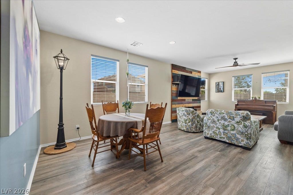 Warm wood flooring and recessed lighting accent this spacious, open-concept living and dining area.