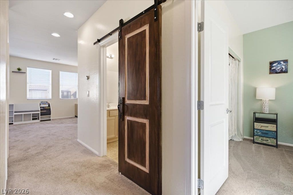 Plush carpeting and an eye-catching sliding barn door define this inviting hallway layout.