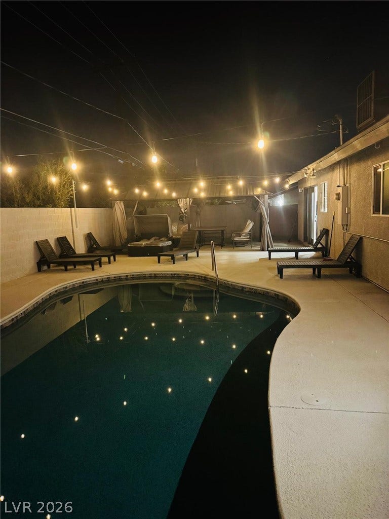 A sparkling in-ground pool is framed by concrete decking and a block wall border.