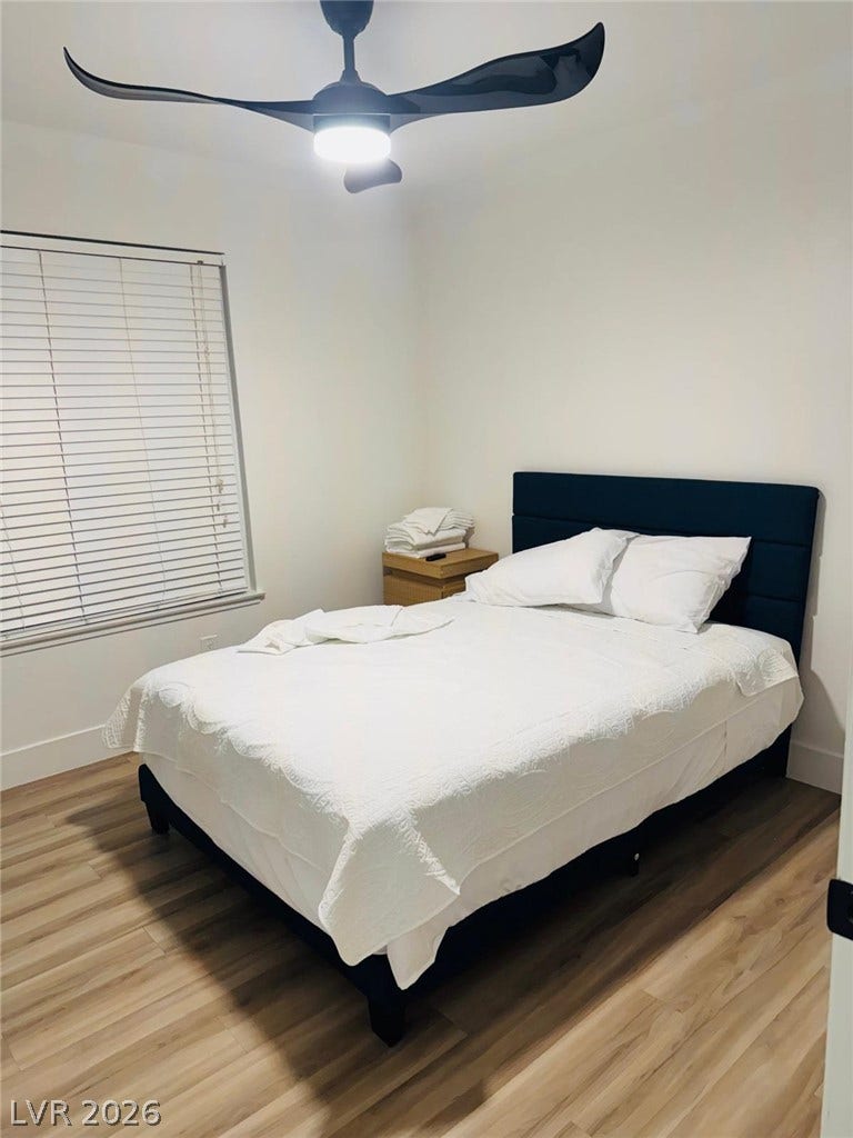 Smooth wood-look flooring and a large window bring classic charm to this restful space.
