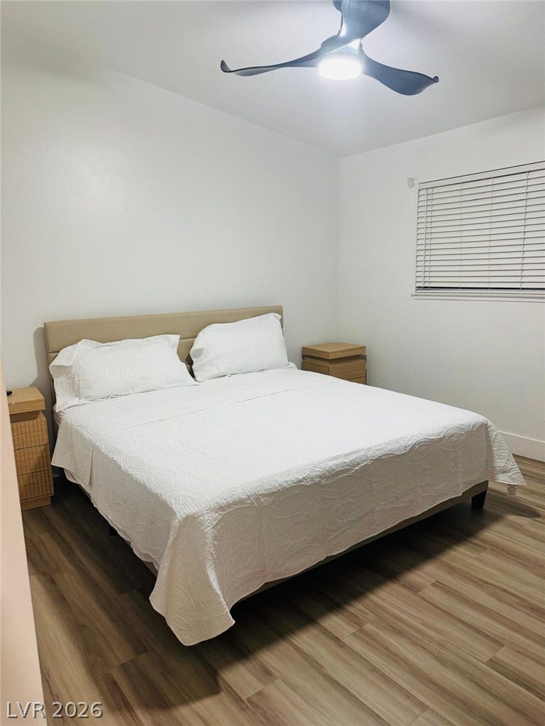 A tranquil sleeping space featuring beautiful wood-plank flooring and a large window.