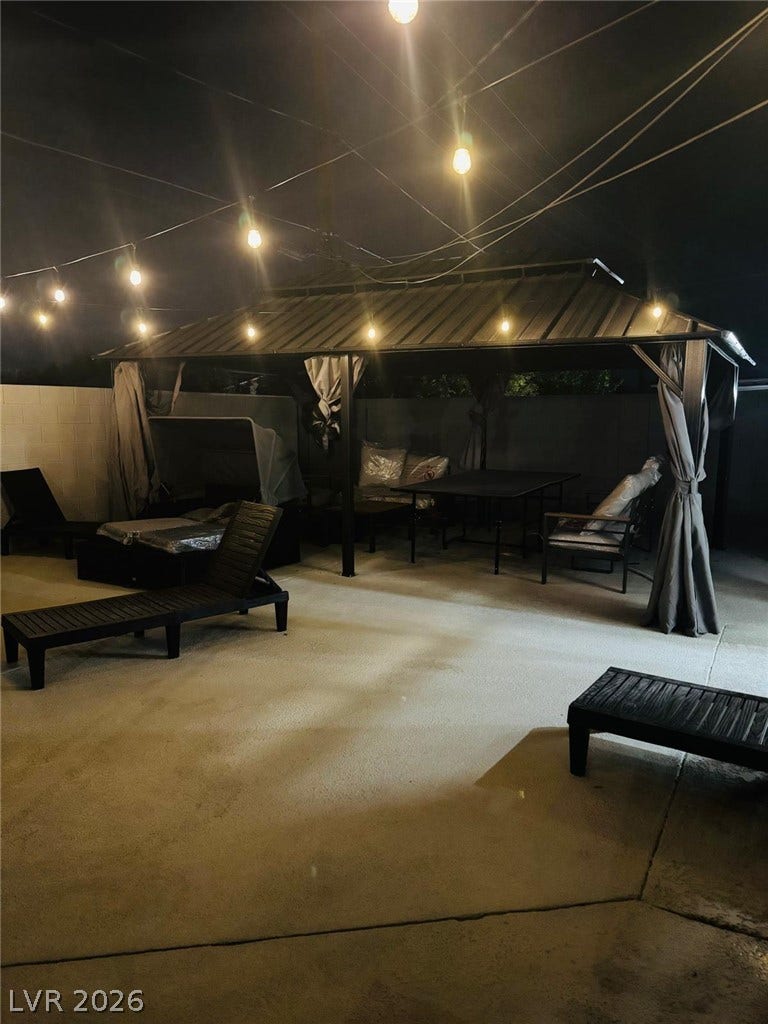 An inviting concrete patio features a large covered gazebo perfect for evening outdoor dining.