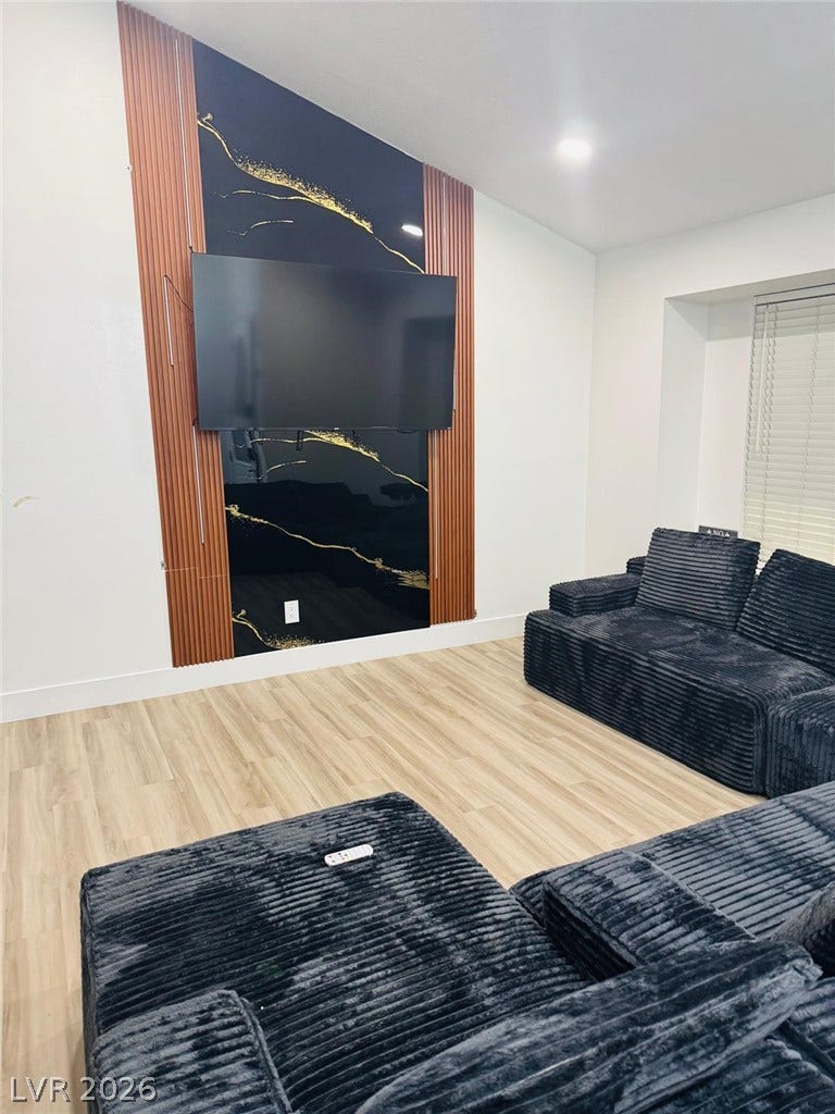 Gleaming wood-look floors complement high ceilings and custom wall panels in this modern living room.