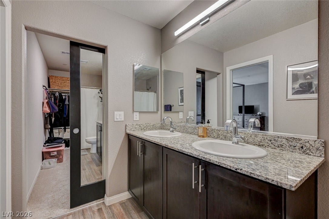 A spacious double vanity features granite countertops and seamless access to the walk-in closet.