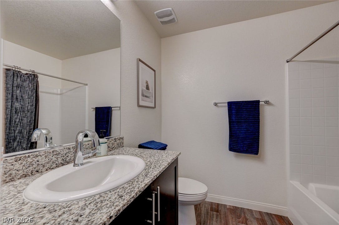 Polished granite countertops and classic wood-look flooring anchor this clean, functional bathroom space.