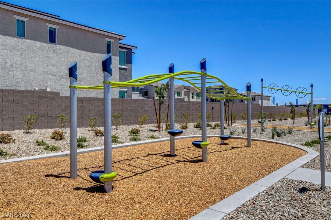 An outdoor playground area sits adjacent to residential structures under a clear blue sky.