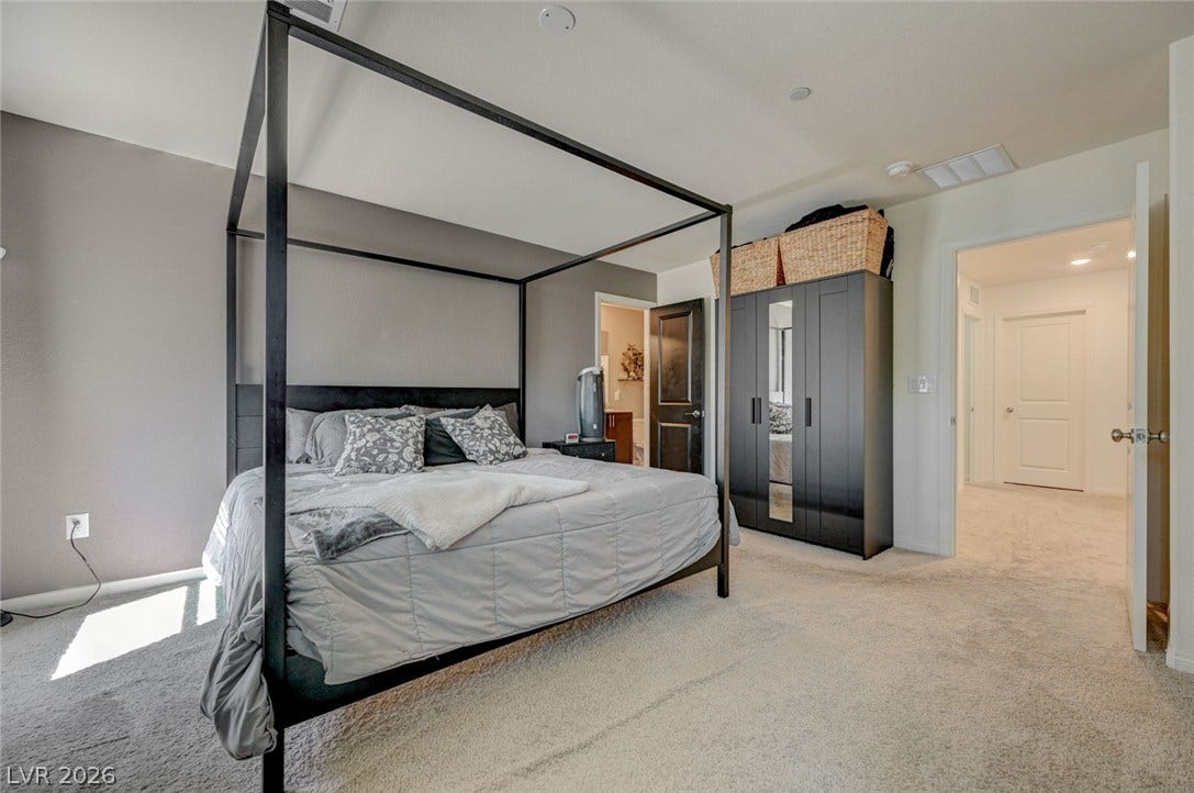 Soft carpeting pairs with neutral walls in this comfortable bedroom space.
