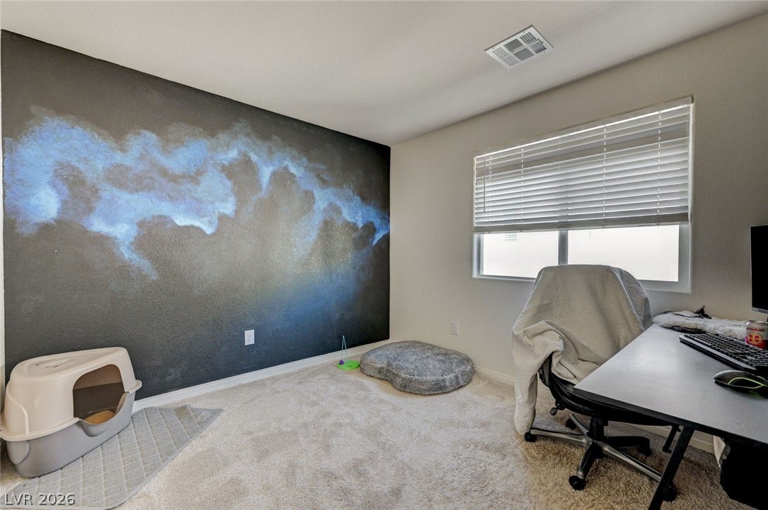 Plush carpeting and a wide window create a comfortable, sunlit environment for work or study.